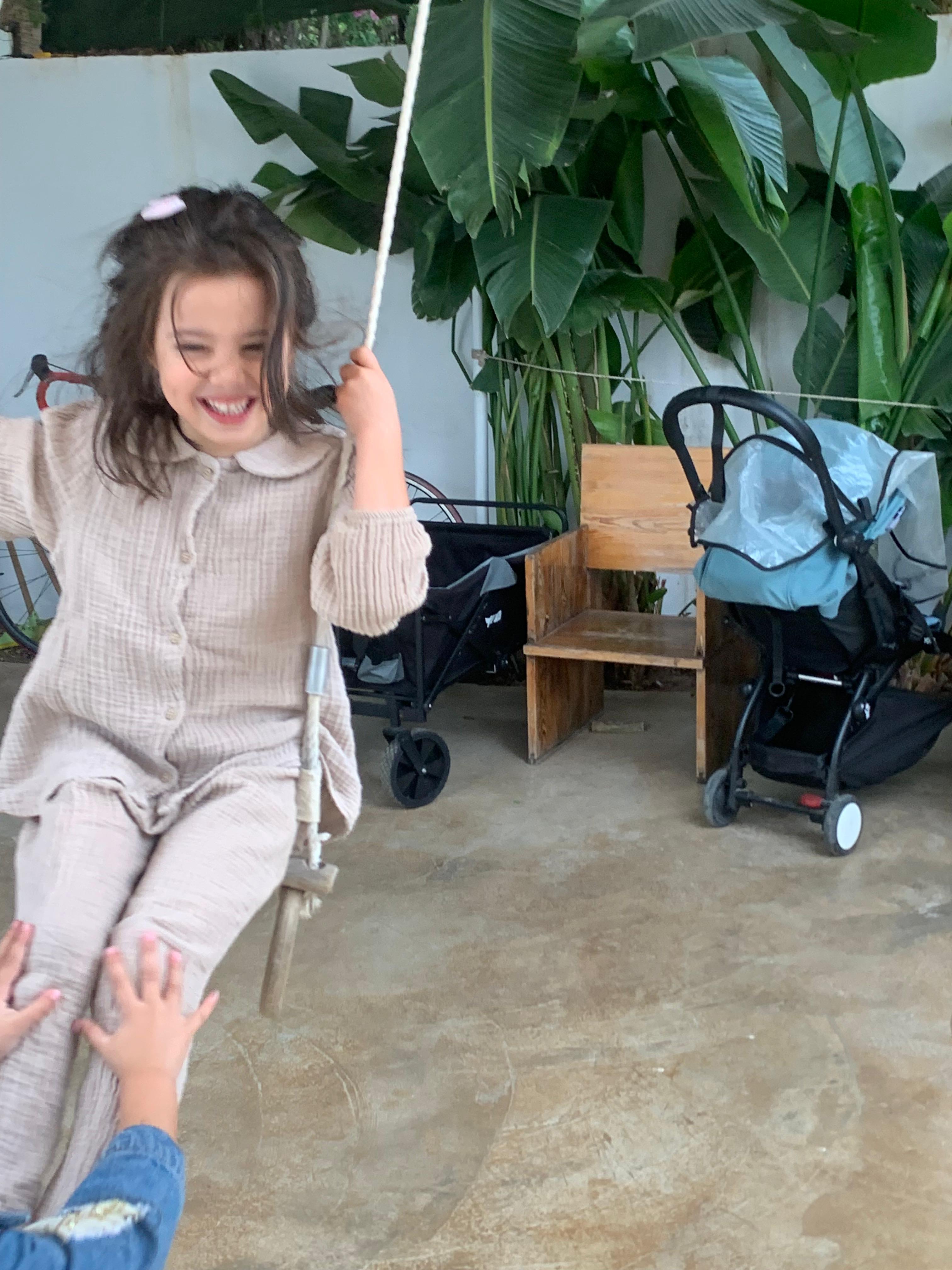 Enfant souriant sur une balançoire à l'école Origami